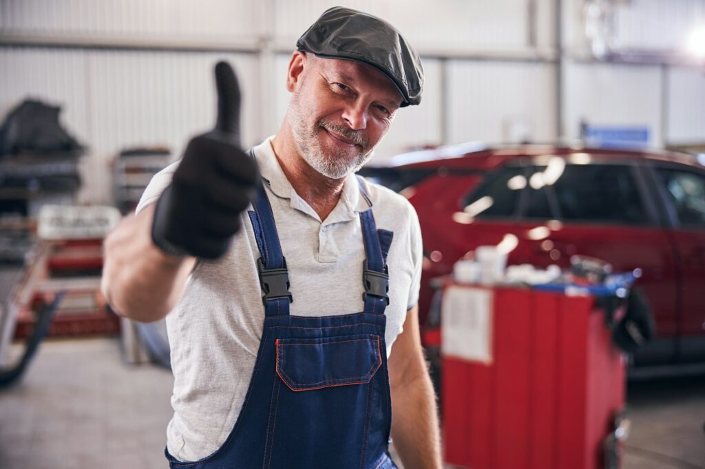 Handsome mechanic giving thumbs up and smiling